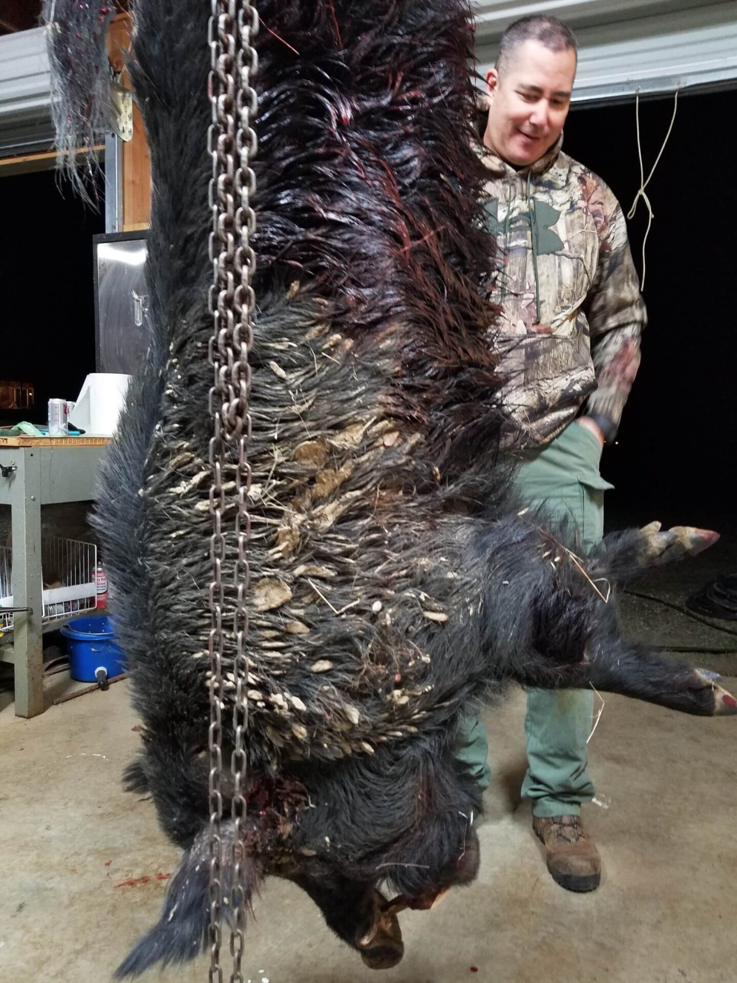 A man standing next to a bear with chains hanging from it.